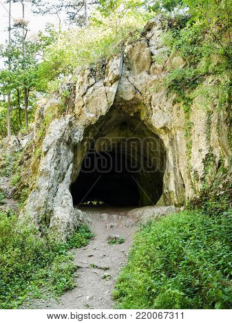 Path leading to the dark cave entrance with silhouettes of people inside