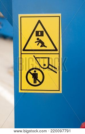 Warning sign on farm machinery.To keep the distance. It is forbidden to stand under the bucket. It is possible to fall. It is possible to obtain a blow on the head.