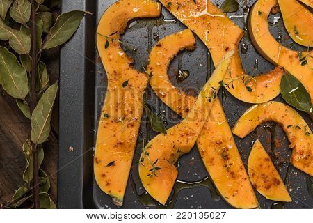 Roasted sliced butternut squash seasoned with salt, sweet pepper, pepper and thyme on baked dish