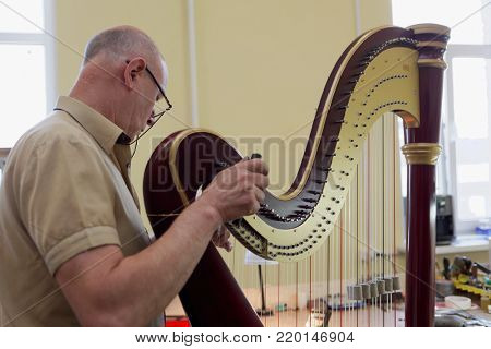 ST. PETERSBURG, RUSSIA - AUGUST 8, 2017: Master tuning the harp in Resonance Harps enterprise. The company revives the production of harps of the Lunacharsky factory founded in 1947