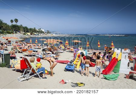 Sanremo, Liguria, Italy - May 23, 2009: People relaxing on a Mediterranean public beach in Sanremo Italy on a hot summer day