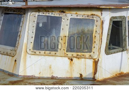 Rusting, fogged windows on wheelhouse of old fishing boat