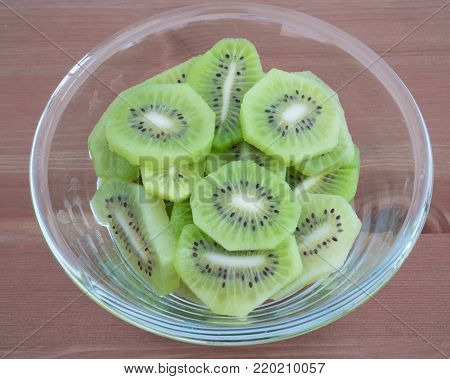 Bowl full with high in vitamins Kiwi fruit slices isolated on wooden background