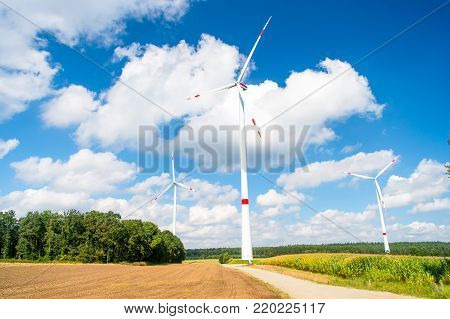 Turbines on field on cloudy blue sky. Wind farm in Lower Saxony, Germany. Global warming, climate change. Alternative energy source. Eco power, green technology concept.