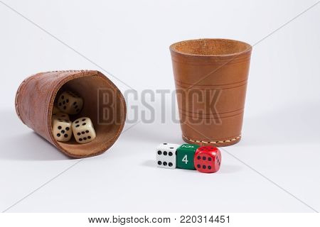 two brown leather cups filled with dice and three white red green colored dice showing six four six isolated on white background