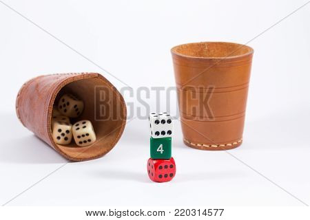 two brown leather cups filled with dice and three white red green colored dice stacked on top of each other showing six four six isolated on white background