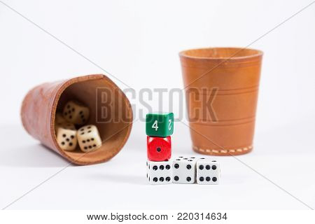 two brown leather cups filled with dice and five white red green colored dice stacked on top of each other showing four one six four six isolated on white background