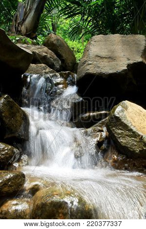 Long exposure shot of flowing water over rocks in the stream. Long exposure make the blurry effect of flowing water. Mountain stream flowing down from hill to valley.