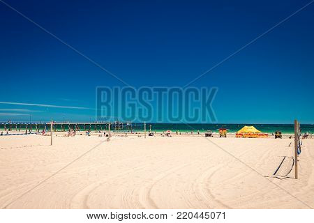 Glenelg, South Australia - February 28, 2016: People with surf life saving patrol at Glenelg beach viewed from Beach House on a bright summer day