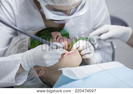 Doctor dentist treats teeth of a beautiful young girl patient. The girl on reception at the dentist. Doctor dentist treats tooth.