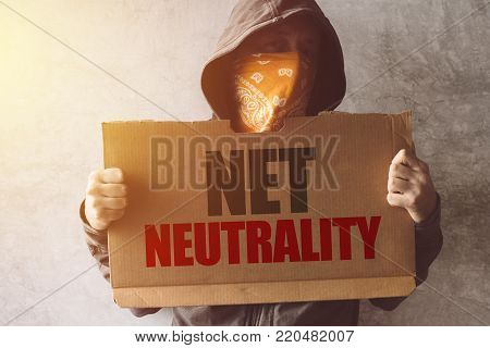 Hooded activist protestor holding Net neutrality protest sign. Man with hoodie and scarf over face taking part in activism and fighting for the cause.