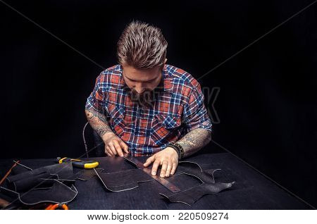 Portrait of leather craftsman working making measupenets in patterns at table in workshop studio