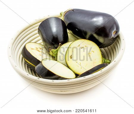 Group of eggplant (aubergine) in rattan bowl, sliced in round circles and one whole, isolated on white background