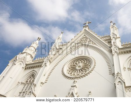 The upper part of the Lourdes Cathedral of white color on the background with the blue sky. View of the Gothic style building in South India, Trichur