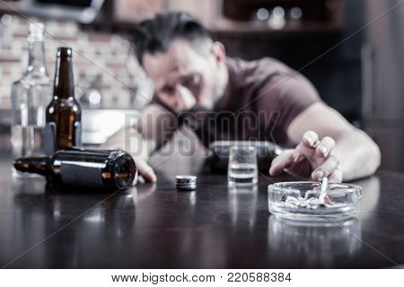 Smoking habit. Selective focus of an ashtray standing on the table with cigarette-butts in it