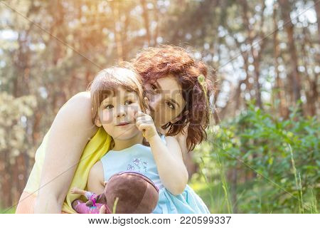 Young mother and little daughter playing in the park on a summer sunny day