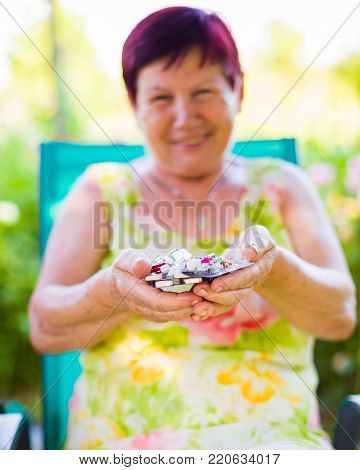 Closeup of elderly woman holding her expensive drugs and being smiling outdoors.