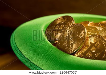 Treasure of golden bitcoins inside a green velvet hat on wooden table to celebrate luck on St Patrick's Day of March 17th