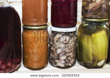 Storage shelves in pantry with homemade canned preserved fruits and vegetables.