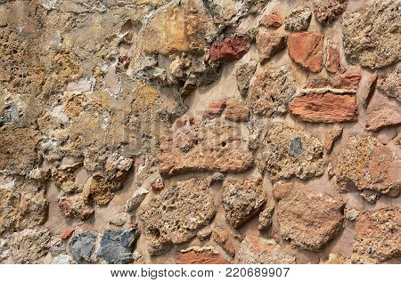 Ancient stone wall. Masonry of old stones and bricks. Beautiful unusual background.