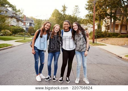 Teen girls on the way to school look to camera, full length