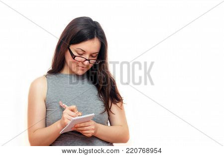 beautiful brunette with glasses writes in a notebook