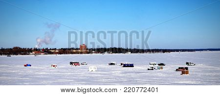Winter Fishing Houses on frozen Lake Bemidji in Minnesota on a late December morning with Bemidji State University in background