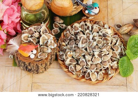 Moringa oleifera oil and seeds on wood background