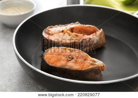 Tasty rainbow trout steaks on frying pan, closeup