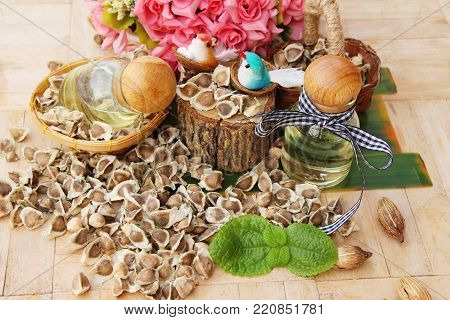 Moringa oleifera oil and seeds on wood background