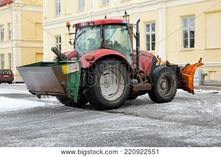 Strangnas, Sweden - February 21, 2016: A tractor in work sanding the square with gravel from the container mounted at the back.