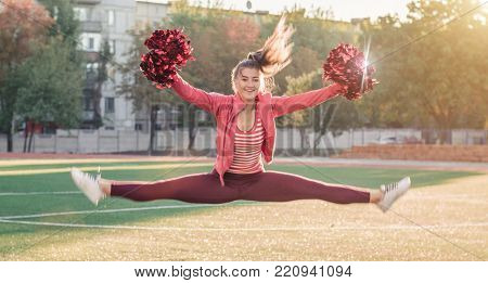 Girl In Pink Sport Suit With Pompoms Doing Splits At The Stadium.