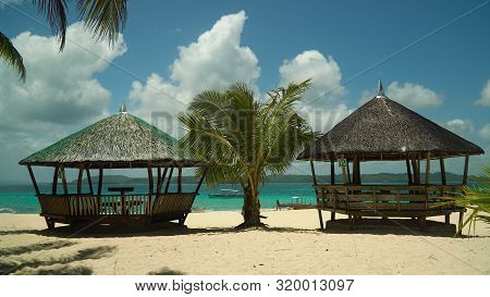 Tropical Beach With Bungalows And Blue Sea. Summer And Travel Vacation Concept