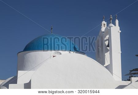 Greece, The Island Of Sikinos.  The Village Square. A View Of The Main Church.  Clear Blue Sky. Brig