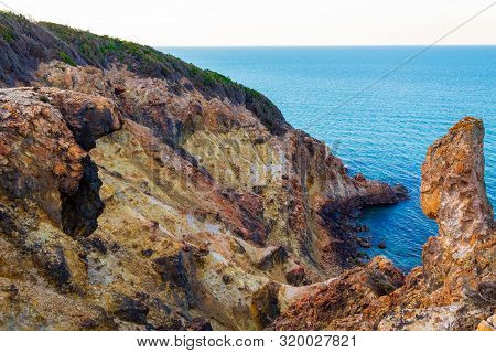 Exotic cliff rock, background sea 

Light brown color rocks and cliff, waves hitting the rocks