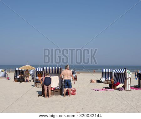 Norderney, Germany, 25 August 2019: People In Bathing Suit Use Beach Korbs On The Island Of Norderne
