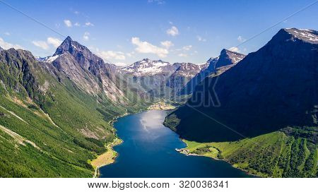 Aerial View On Geiranger Town, Harbor And Fjord In More Og Romsdal County In Norway Famous For His B