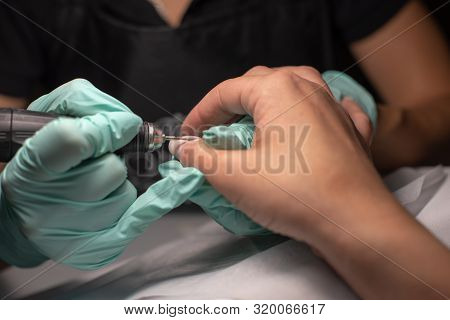 A Manicure Hand With A Nail Lies On A Manicure Hand In Blue Hygienic Gloves.hands On The Manicure Of