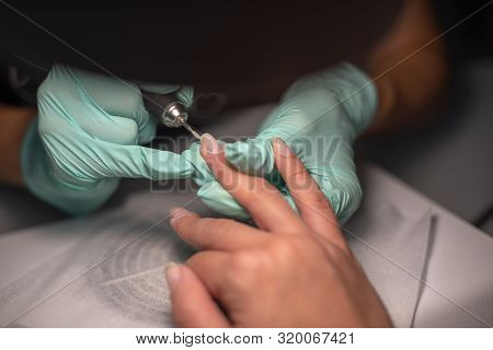 A Manicure Hand With A Nail Lies On A Manicure Hand In Blue Hygienic Gloves.hands On The Manicure Of