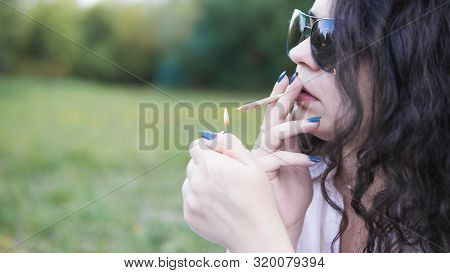 Girl Smoking Medical Marijuana Joint Outdoors, Close-up. Cannabis Is A Concept Of Herbal Medicine.