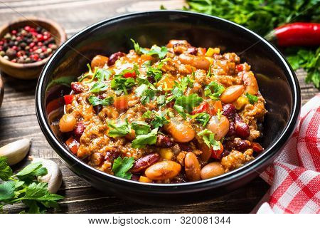 Chili Con Carne With Meat, Beans And Vegetables On Dark Wooden Table Close Up. Traditional Mexican F
