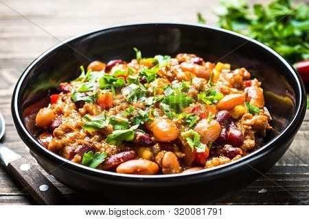 Chili Con Carne With Meat, Beans And Vegetables On Dark Wooden Table Close Up. Traditional Mexican F