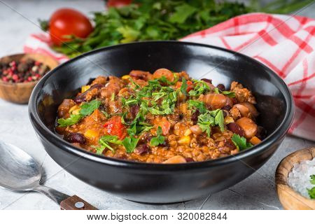 Chili Con Carne From Meat, Beans And Vegetables In Black Plate On Stone Table. Traditional Mexican F
