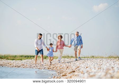 Multigeneration Family On A Holiday Walking By The Lake, Holding Hands.