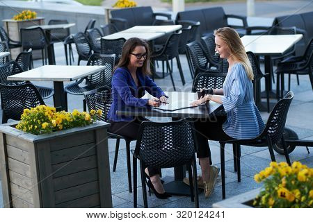 Two Cooperative Workers Are Disscussing New Project Outside Office, At Caffeteria At Nice Summer Day