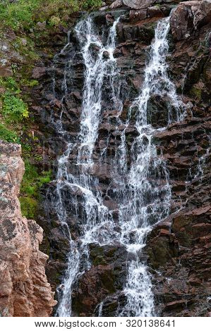 Mountain Rivulet Flowing From A Lake By A Waterfall Along The Steep, Rocky Slopes Of The Coast In Th