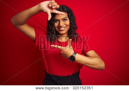 Beautiful transsexual transgender woman wearing t-shirt over isolated red background smiling making frame with hands and fingers with happy face. Creativity and photography concept.