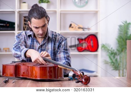 Young handsome repairman repairing cello