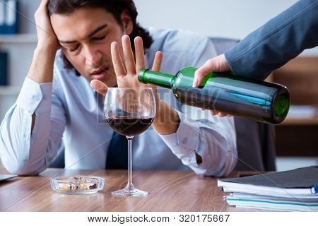Male employee drinking alcohol and smoking cigarettes at workpla