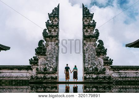 Young Couple Standing In Temple Gates And Holding Hands Of Each Other At Lempuyang Luhur Temple In B